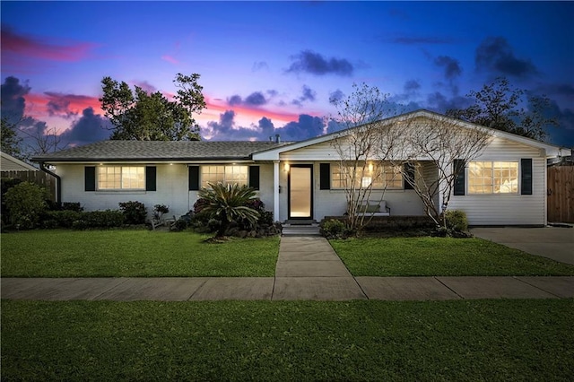 ranch-style house with brick siding, fence, and a yard