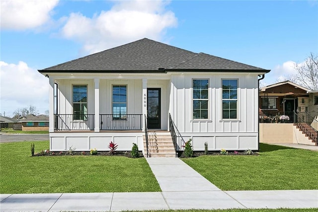 view of front of property with a porch, board and batten siding, a front yard, and a shingled roof