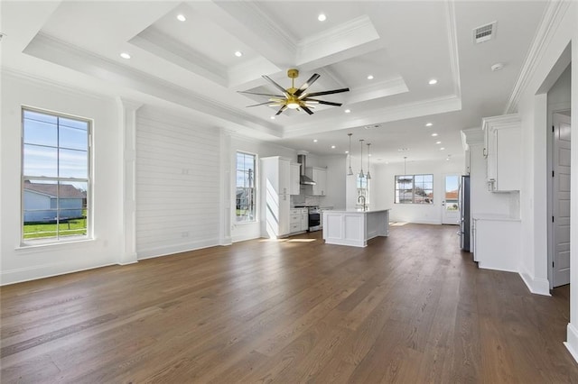 unfurnished living room with ceiling fan, dark wood-style flooring, visible vents, baseboards, and ornamental molding