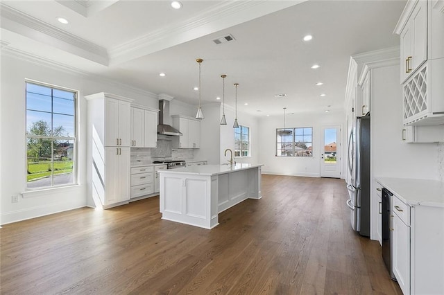 kitchen featuring dark wood-style flooring, crown molding, stainless steel appliances, light countertops, and wall chimney exhaust hood