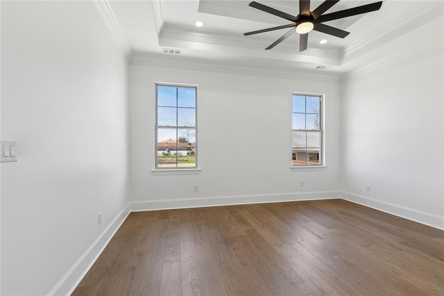 unfurnished room featuring dark wood-type flooring, a tray ceiling, visible vents, and baseboards