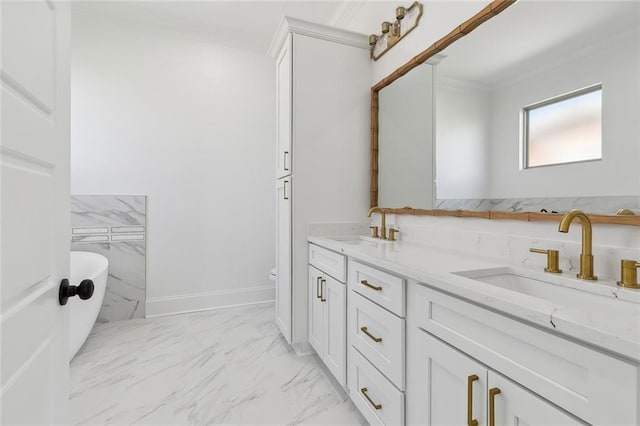 full bathroom with marble finish floor, crown molding, a freestanding tub, and a sink