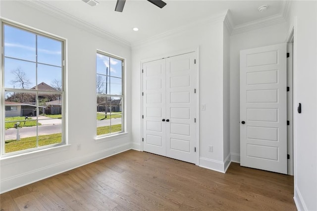 interior space featuring crown molding, baseboards, and wood finished floors