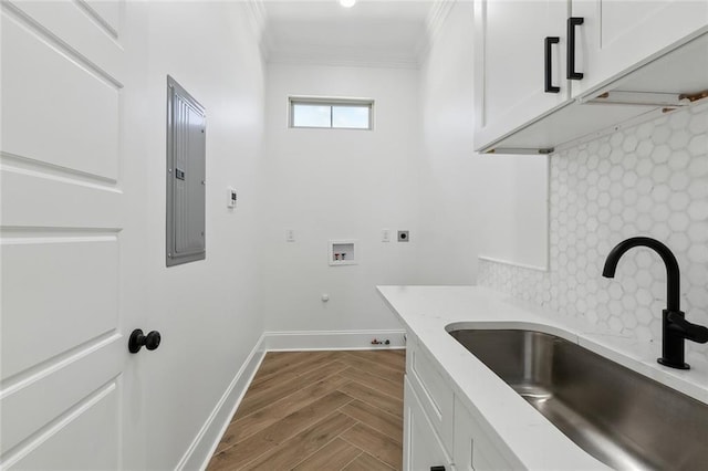 laundry room with crown molding, hookup for a washing machine, cabinet space, a sink, and baseboards