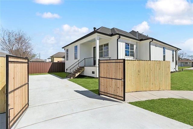 view of front of home featuring a fenced front yard, a gate, a front lawn, and board and batten siding