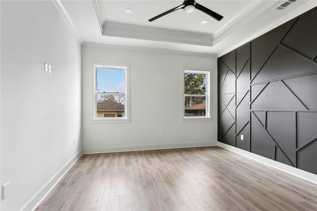 spare room featuring ornamental molding, a raised ceiling, visible vents, and a healthy amount of sunlight