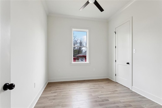 spare room with ornamental molding, light wood-type flooring, a ceiling fan, and baseboards