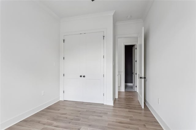 spare room with light wood-style floors, baseboards, and ornamental molding