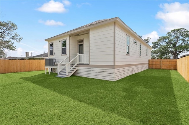 back of house with a fenced backyard, cooling unit, and a lawn