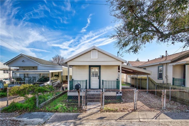 view of front of property featuring a fenced front yard, a gate, an attached carport, and a porch