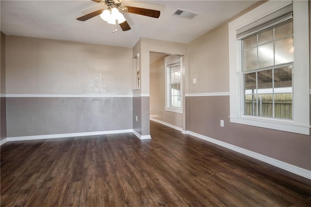 unfurnished room with a ceiling fan, dark wood-style flooring, visible vents, and baseboards