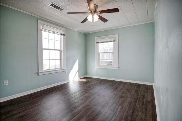 empty room with baseboards, visible vents, a ceiling fan, dark wood-style flooring, and crown molding