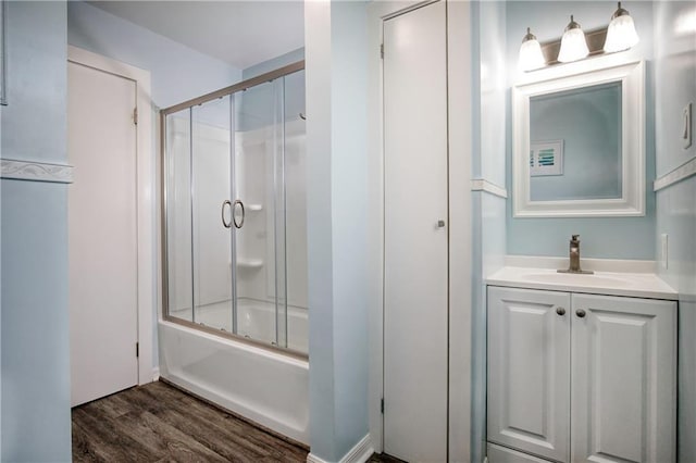 full bath featuring combined bath / shower with glass door, wood finished floors, and vanity