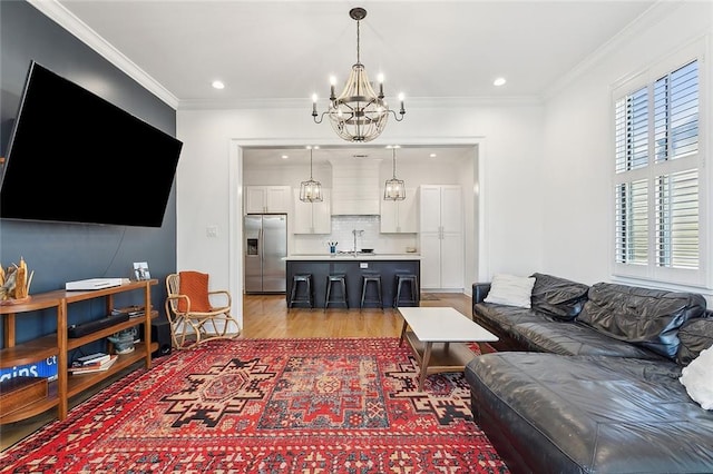 living area featuring recessed lighting, light wood-style floors, a chandelier, and ornamental molding