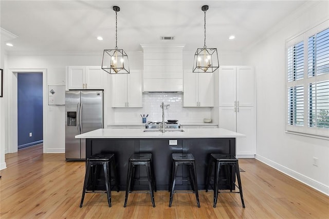 kitchen featuring visible vents, a breakfast bar, light countertops, and stainless steel refrigerator with ice dispenser