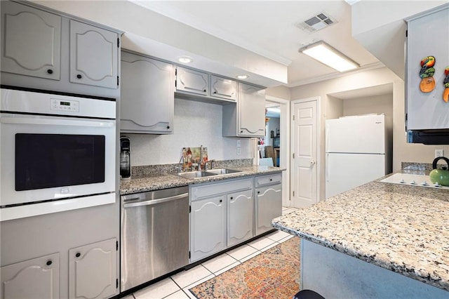 kitchen featuring white appliances, visible vents, crown molding, a sink, and light tile patterned flooring