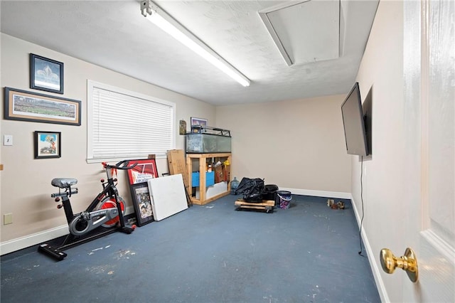 exercise area featuring attic access and baseboards