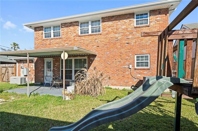 rear view of house with a patio area, a yard, and brick siding