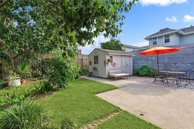 view of yard with an outbuilding, a fenced backyard, a patio, and a shed