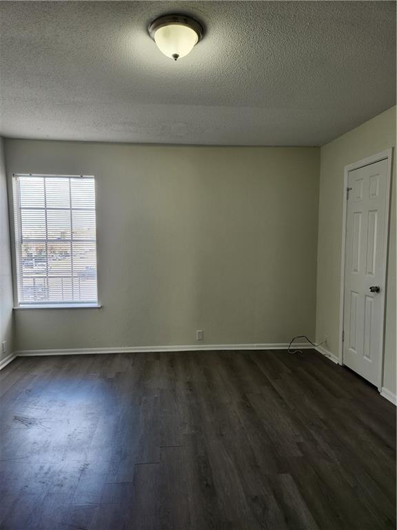 spare room featuring dark wood-style floors, a textured ceiling, and baseboards