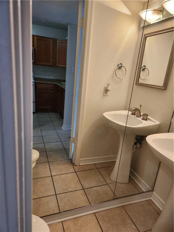 bathroom featuring toilet, tile patterned flooring, and baseboards