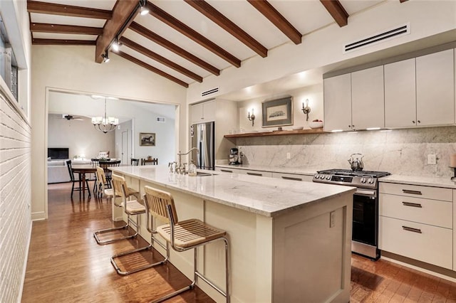 kitchen featuring visible vents, appliances with stainless steel finishes, backsplash, wood finished floors, and a sink