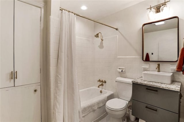 full bathroom featuring toilet, recessed lighting, vanity, tile walls, and shower / bath combo