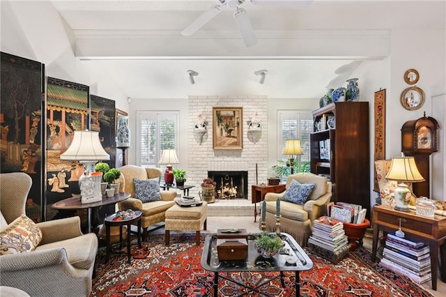 living area with vaulted ceiling with beams, a fireplace, ornamental molding, and ceiling fan