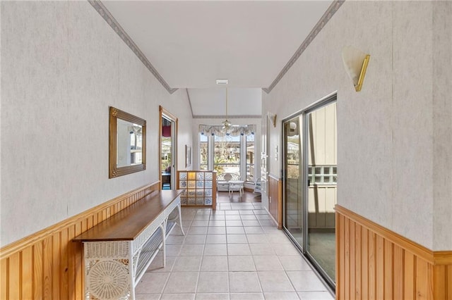 corridor featuring light tile patterned floors, wood walls, wainscoting, and crown molding