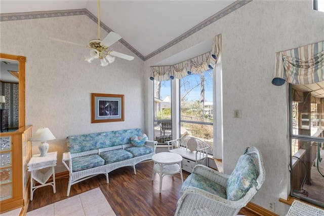 living room featuring wood finished floors, crown molding, wallpapered walls, lofted ceiling, and ceiling fan