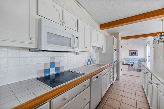 kitchen featuring white appliances, tile counters, white cabinets, and a textured ceiling