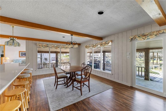 dining space featuring beam ceiling, a chandelier, a textured ceiling, and dark wood-style flooring