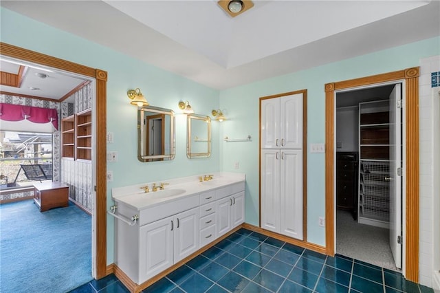 bathroom featuring baseboards, double vanity, a sink, tile patterned flooring, and a closet