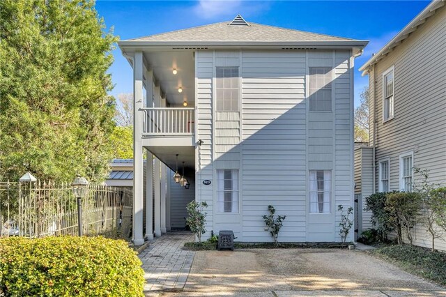 back of house with a balcony, fence, and a shingled roof