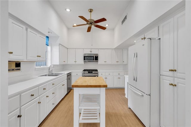 kitchen with stainless steel appliances, visible vents, white cabinets, a sink, and butcher block countertops