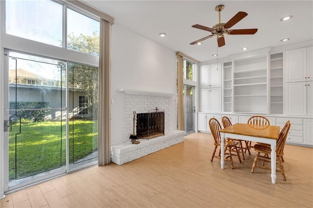 dining room with built in features, recessed lighting, a brick fireplace, and light wood-style flooring