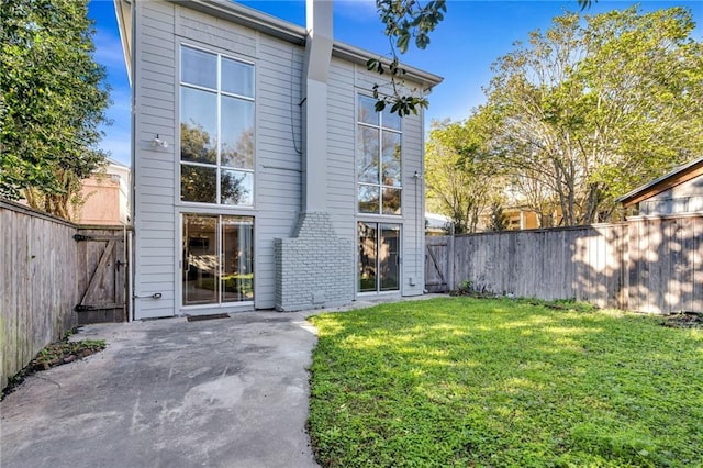 rear view of property featuring a patio, a lawn, and a fenced backyard