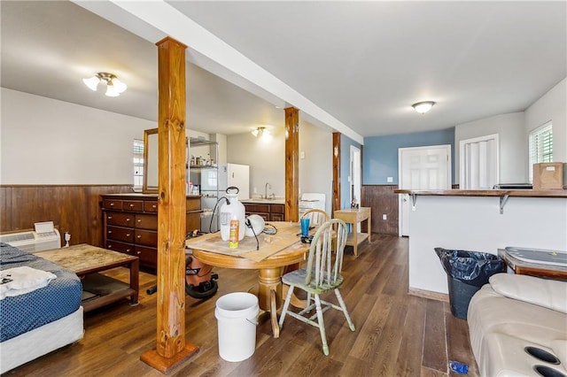 dining area with a wainscoted wall, wood finished floors, and wood walls