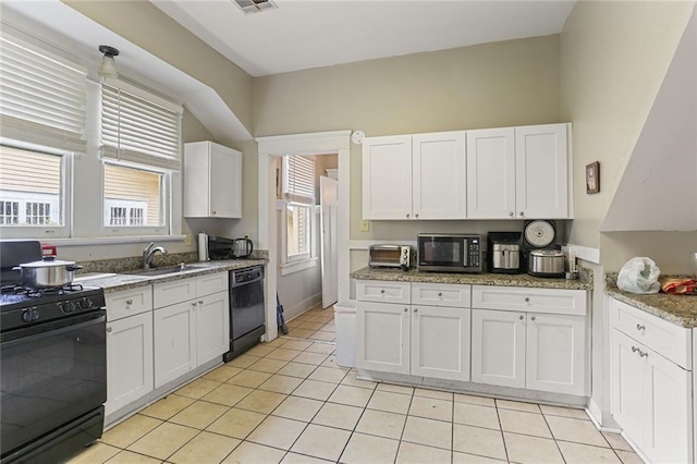 kitchen with light tile patterned floors, black appliances, a sink, and white cabinetry