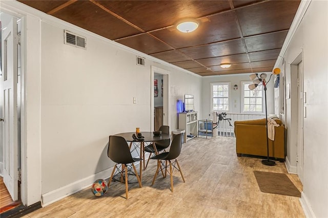 dining area featuring light wood-style flooring, visible vents, baseboards, and ornamental molding