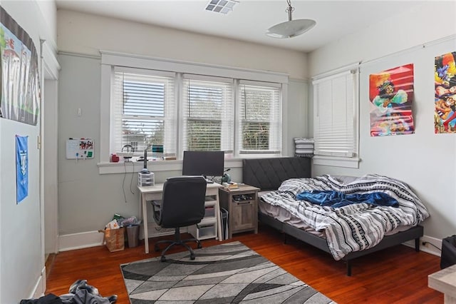 bedroom with visible vents, baseboards, and wood finished floors