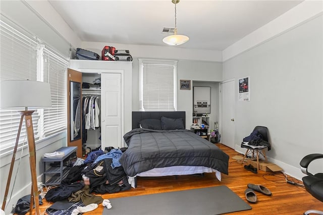 bedroom featuring a closet, visible vents, baseboards, and wood finished floors