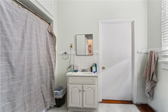 full bath with wainscoting, vanity, and tile walls