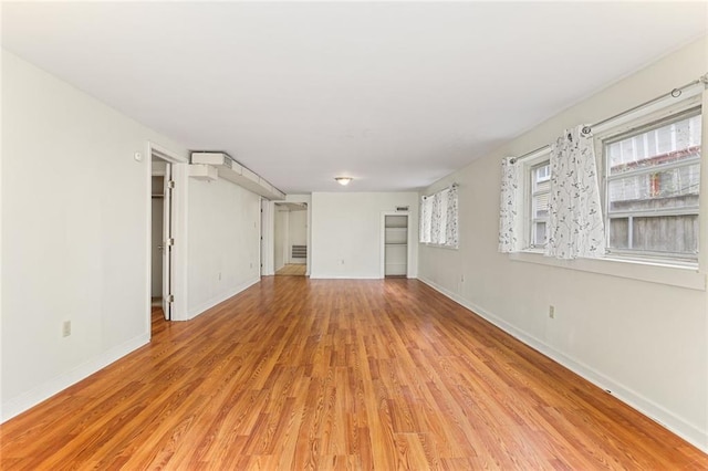 unfurnished living room with light wood-type flooring and baseboards