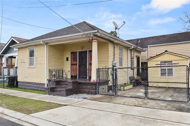 view of front of house featuring covered porch, a gate, fence, and roof with shingles