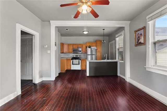 kitchen featuring stainless steel appliances, brown cabinets, dark wood finished floors, and baseboards