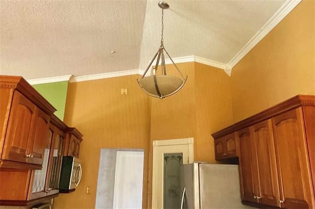 room details with stainless steel microwave, ornamental molding, brown cabinetry, and freestanding refrigerator