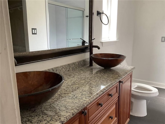 full bath featuring vanity, a shower with door, toilet, and tile patterned flooring