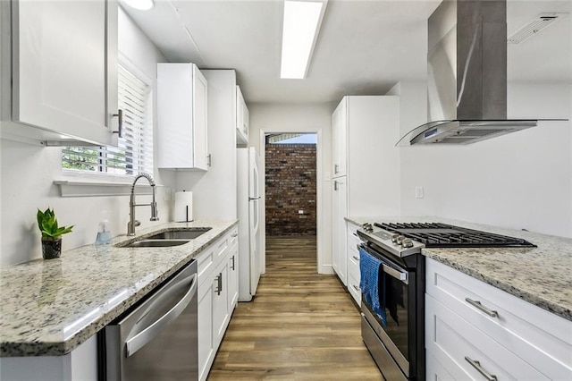 kitchen featuring stainless steel appliances, white cabinets, a sink, wood finished floors, and extractor fan