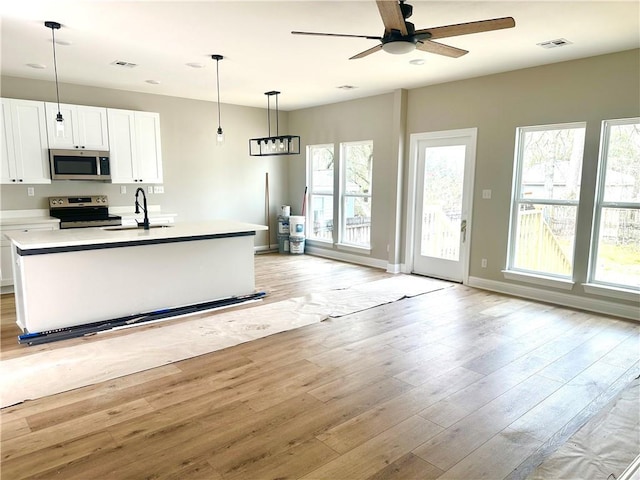 kitchen featuring visible vents, stainless steel appliances, light countertops, light wood-style floors, and a sink